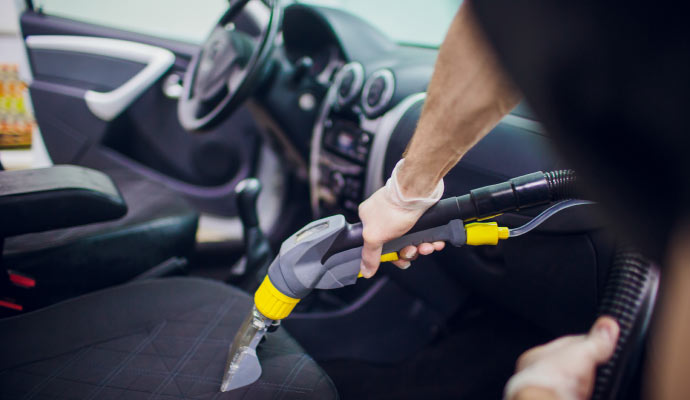 Person cleaning car seat with vacuum cleaner