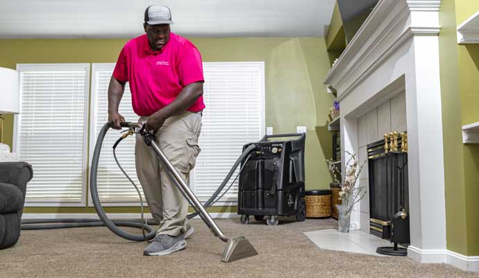 Person cleaning carpet with equipment