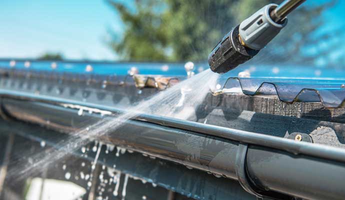 A pressure washer being used to clean a gutter