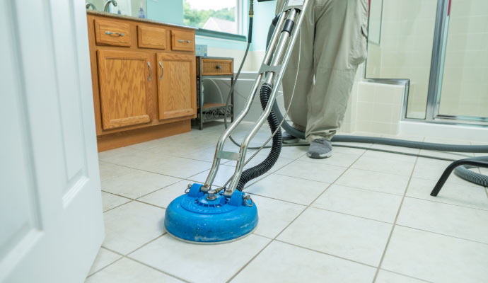 Person cleaning tile floor with equipment