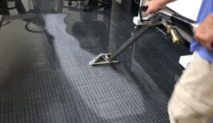 Person cleaning water on the floor with cleaning machine