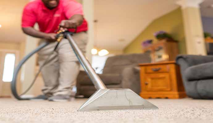 Person cleaning carpet with carpet cleaning machine