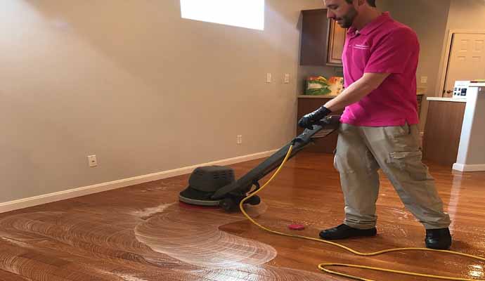 Person cleaning wooden floor using equipment